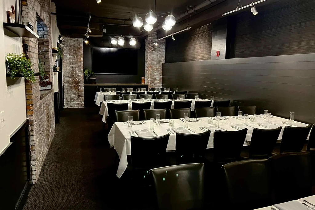 Modern restaurant dining room with set tables and dark brick walls.