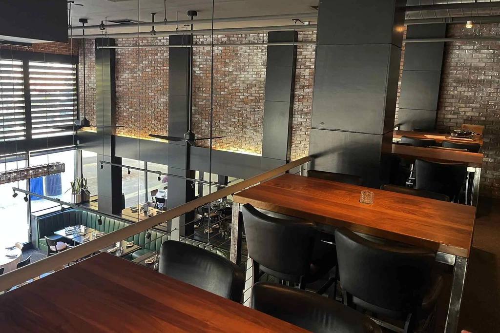 Two-story industrial restaurant interior with brick walls and varied seating.