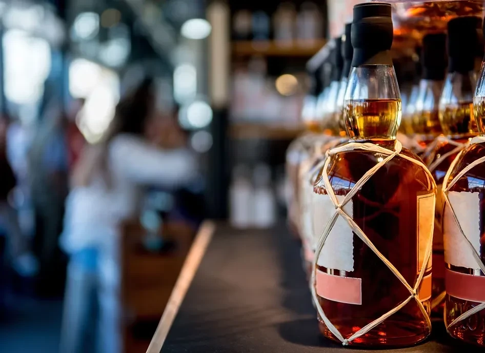 Several amber spirit bottles with netting on a blurred bar counter.