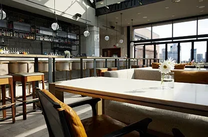 Bright, modern restaurant bar interior, city view, no people.