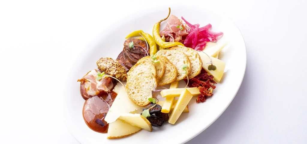 Gourmet charcuterie platter with cheeses, cured meats, bread, and condiments.