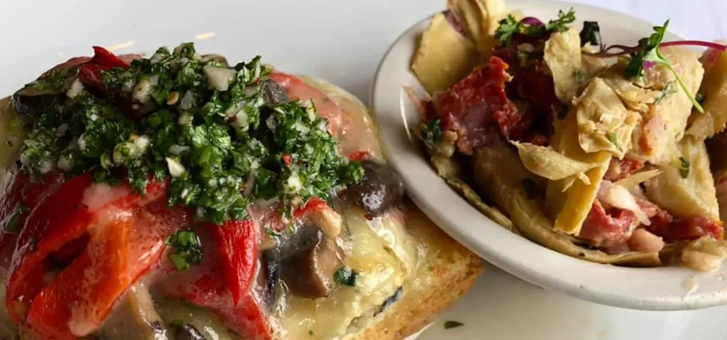 Top-down: two plated dishes, focaccia with peppers and a pasta salad.