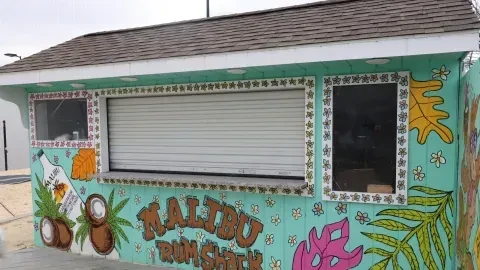 Colorful aqua blue Malibu Rum Shack with tropical murals and bottle.