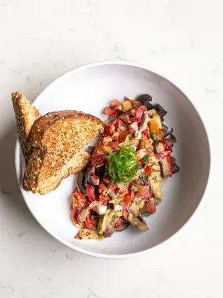 Scrambled eggs with colorful salsa, green onions, and multi-grain toast.