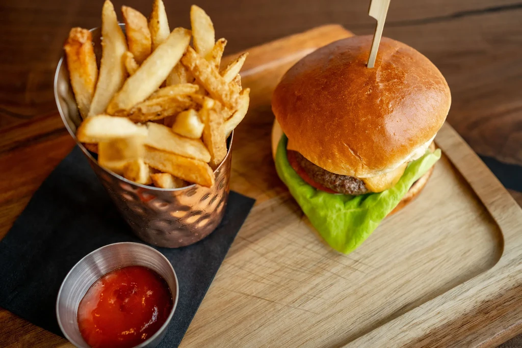 Cheeseburger and french fries with ketchup on a wooden board.