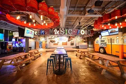 Industrial-chic food hall interior with vintage food truck and arcade games.