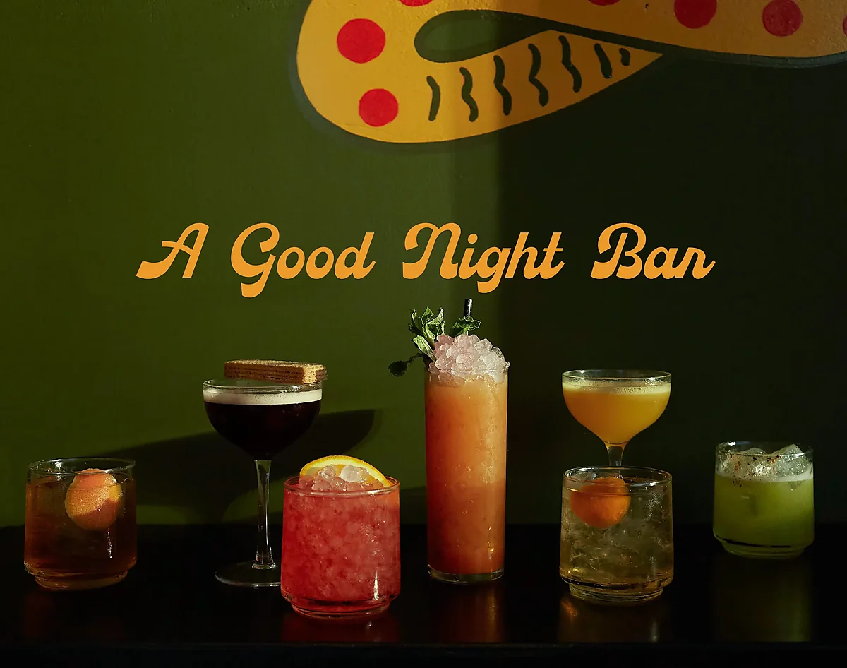 Row of six cocktails on bar against green painted wall
