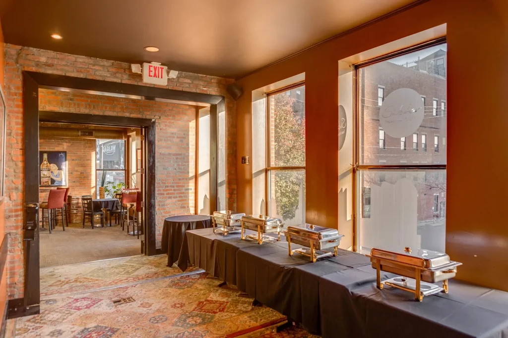 Restaurant interior with buffet table, chafing dishes, and urban window view.