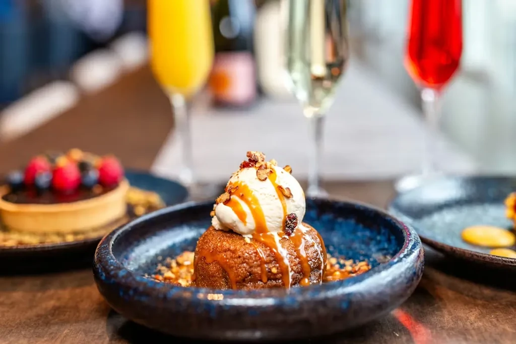 Warm pudding with ice cream, caramel, nuts, berries in a blue bowl.
