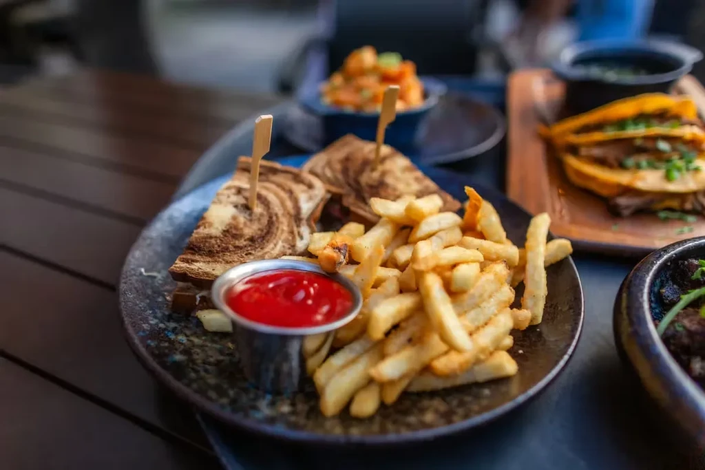 Marbled rye sandwich, french fries, and ketchup on a wooden table.