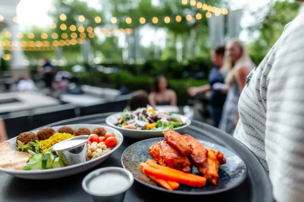 Falafel bowl and buffalo wings on a tray at an outdoor patio.