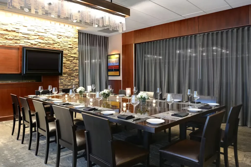 Well-appointed private dining room with long set table and stone wall.