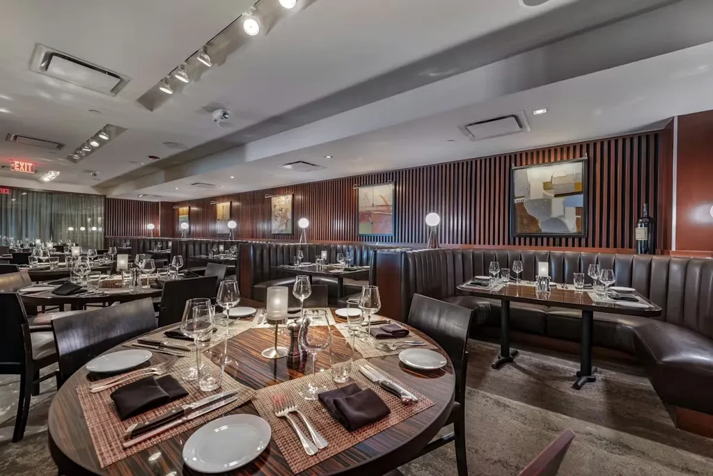 Empty fine dining restaurant with meticulously set tables and booths.