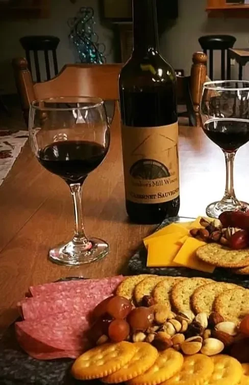 Walker's Mill Cabernet Sauvignon, two wine glasses, and a charcuterie platter.