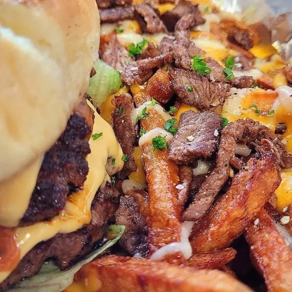 Cheeseburger and loaded fries topped with steak, cheese, and sauce.