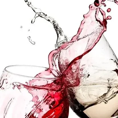 Dynamic splash of red and light wine from two clinking glasses.