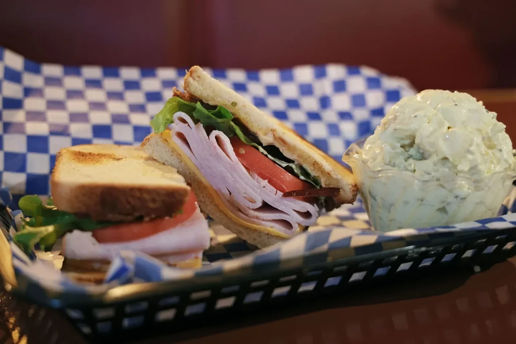 Classic club sandwich with bacon and potato salad in a deli basket.