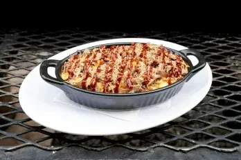 Pulled pork macaroni and cheese with barbecue sauce in a cast iron dish.