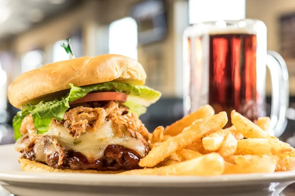 Close-up of a burger, french fries, and a beer mug.