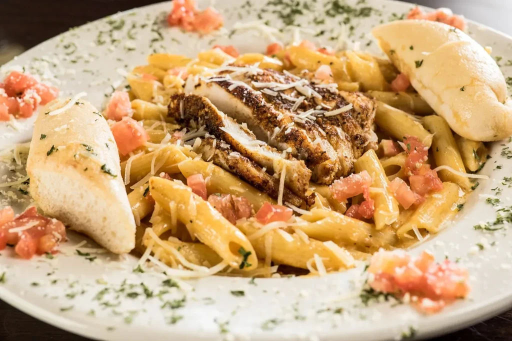 Creamy penne pasta with grilled chicken, tomatoes, herbs, and garlic bread.