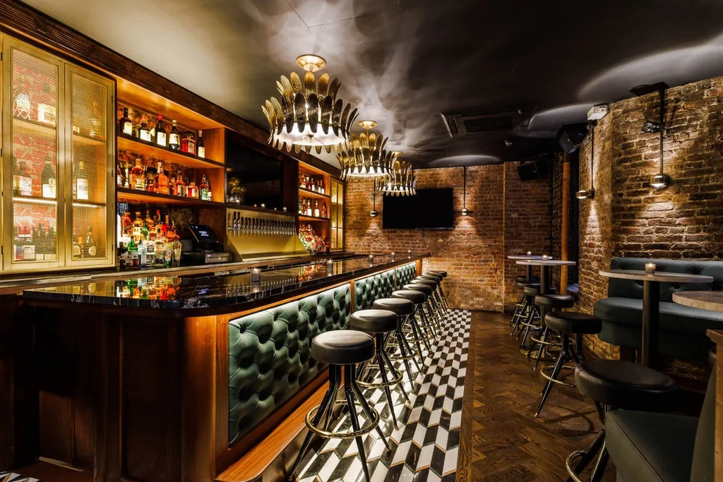 A modern bar with a black and white tiled floor and brick walls.