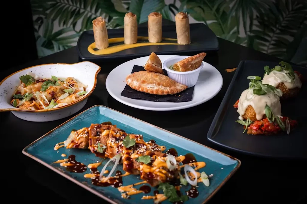 Multiple small dishes and appetizers on a table with a leafy background.