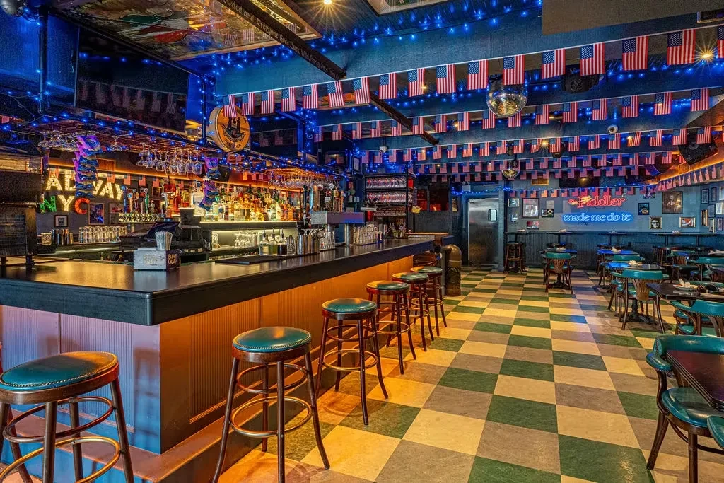 A vibrant bar interior with many American flags and blue lights.