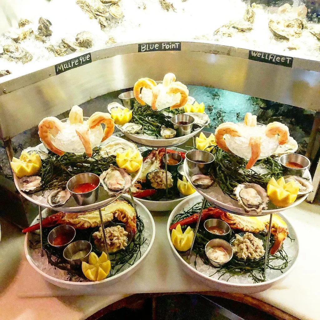Two tiered seafood towers with oysters, shrimp, and lobster over ice.