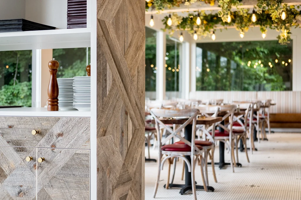 A restaurant interior with wooden furniture, stacked plates, and string lights.