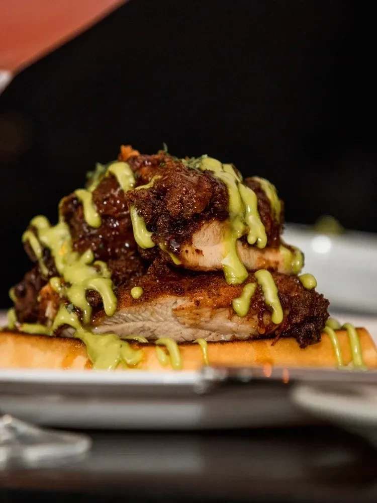Crispy chicken pieces and avocado sauce on a waffle.