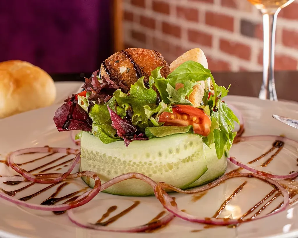 Gourmet salad with fried goat cheese, cucumber, onion, and balsamic glaze.