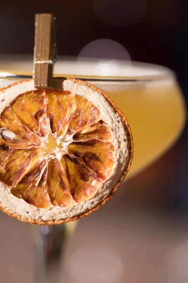 Close-up of a dried orange slice clipped to a cocktail glass.