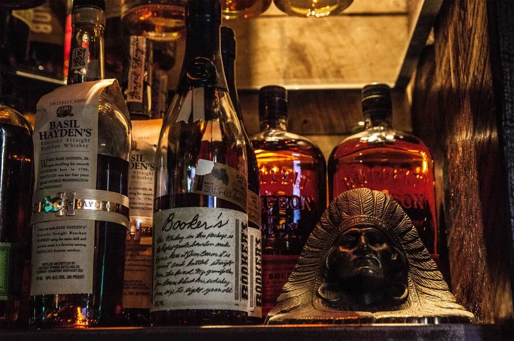 Close-up of bourbon bottles and a Native American headdress sculpture.