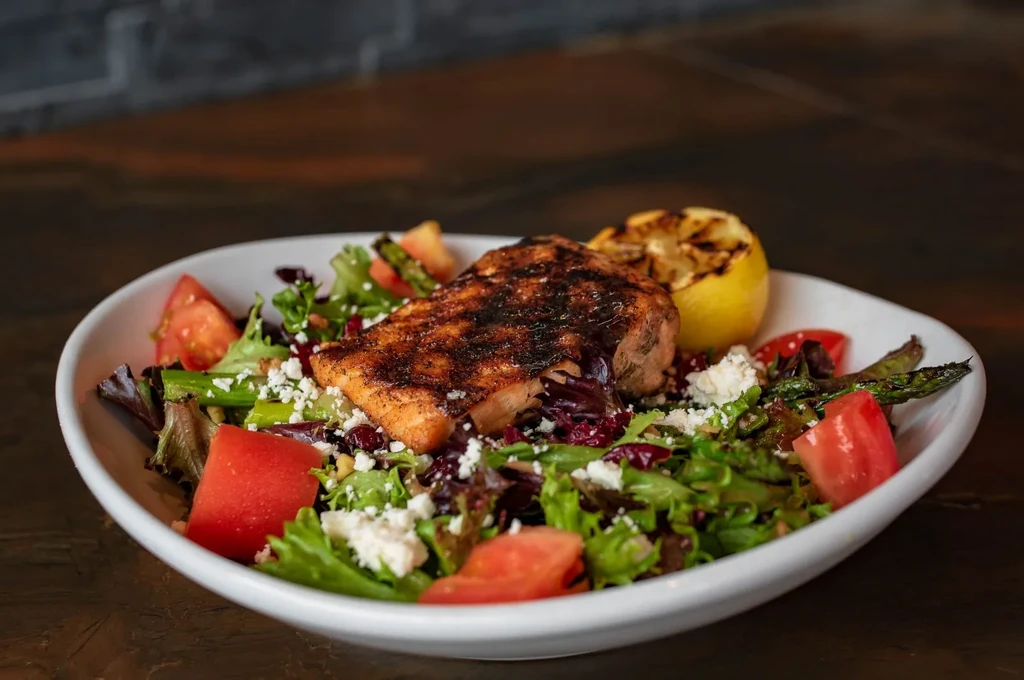 Grilled salmon salad with greens, feta, asparagus, and charred lemon.