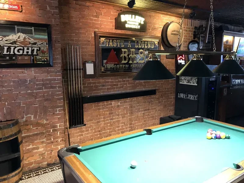 A pool table with racked balls and a cue ball in a brick-walled bar.