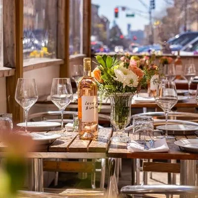 A bottle of rose wine and flowers on a restaurant patio.