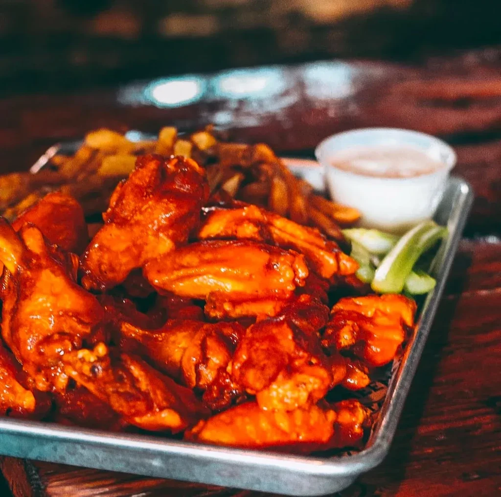 A tray of buffalo wings, french fries, ranch, and celery sticks.