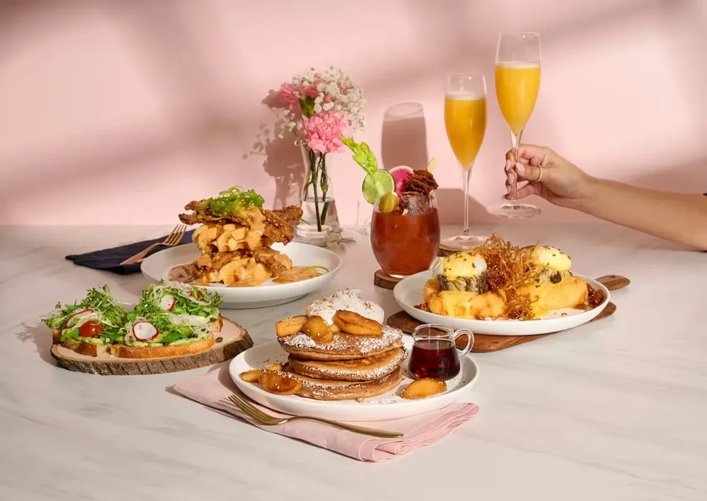 Table with avocado toast, chicken & waffles, pancakes, French toast, and mimosas.