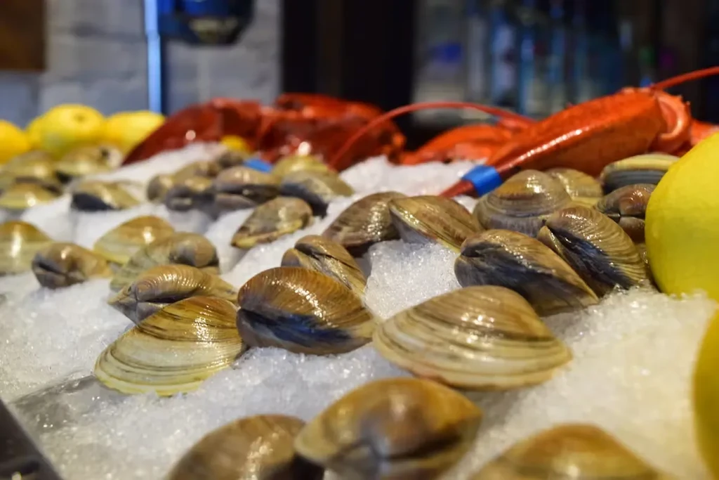 Clams and lobsters on ice, with lemons, at a seafood market.