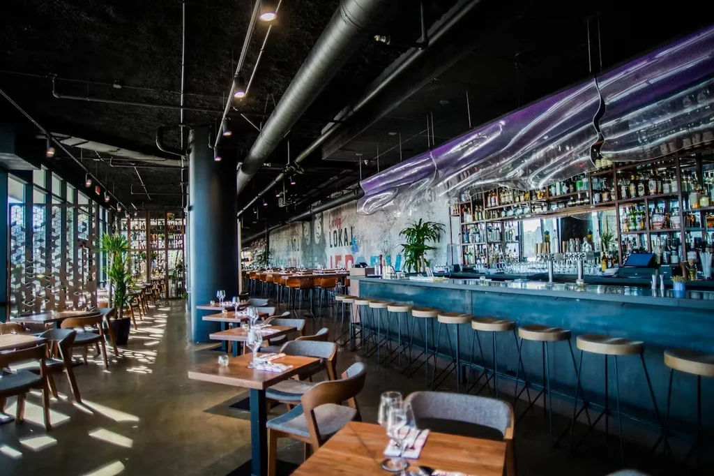 Interior of a modern, empty restaurant with a bar and dining tables.