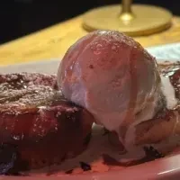 French toast with powdered sugar and a scoop of melting vanilla ice cream.