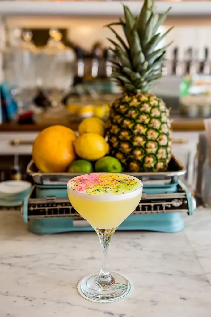 Colorful cocktail with pineapple, oranges, lemons, and limes on a bar.