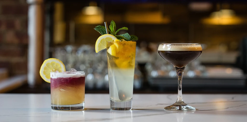 Three different cocktails on a white bar counter.