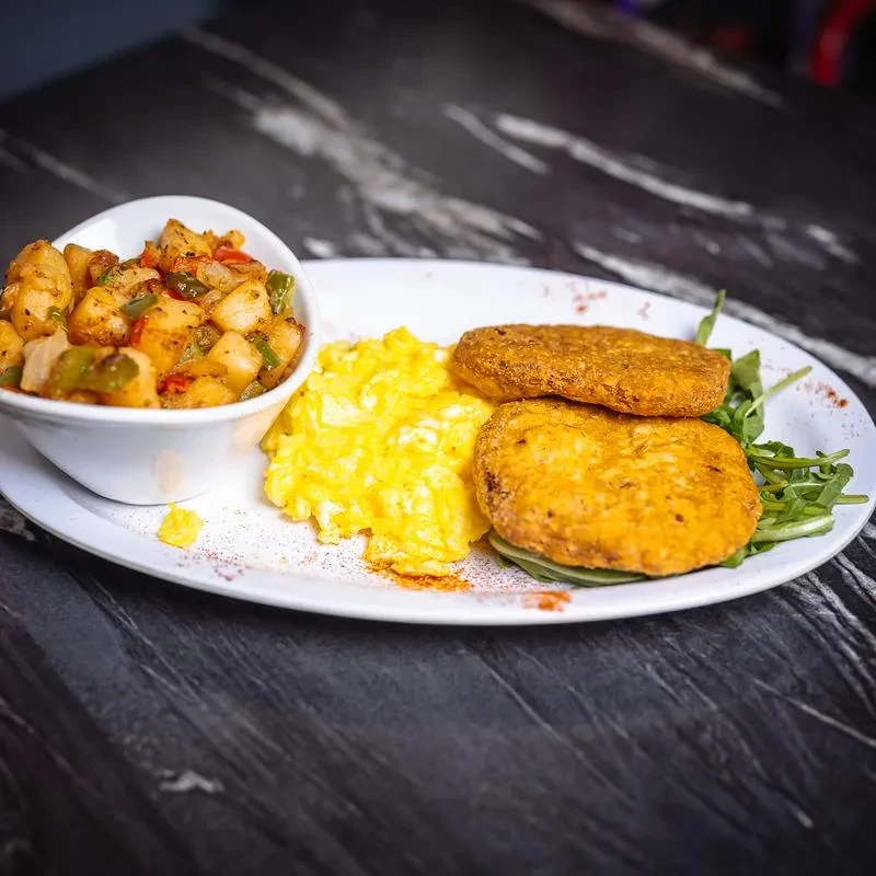 Breakfast plate with scrambled eggs, hash browns, and a bowl of potatoes.