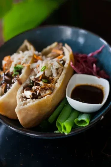 Two filled flatbreads with meat, cabbage slaw, sauce, and pickled cabbage.