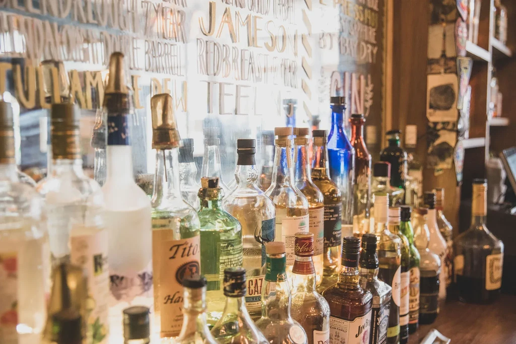 A close-up of various liquor bottles lined up on a bar.