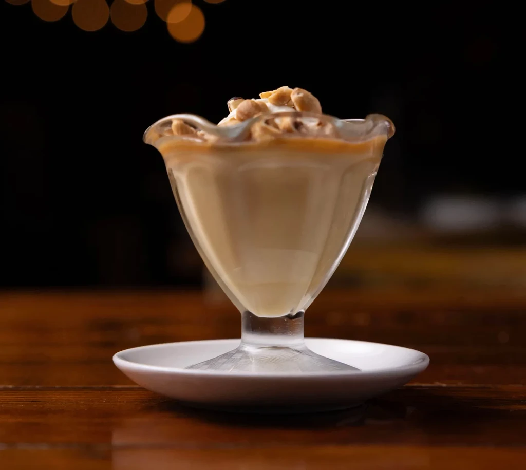 Dessert in a glass dish with whipped cream and nuts.