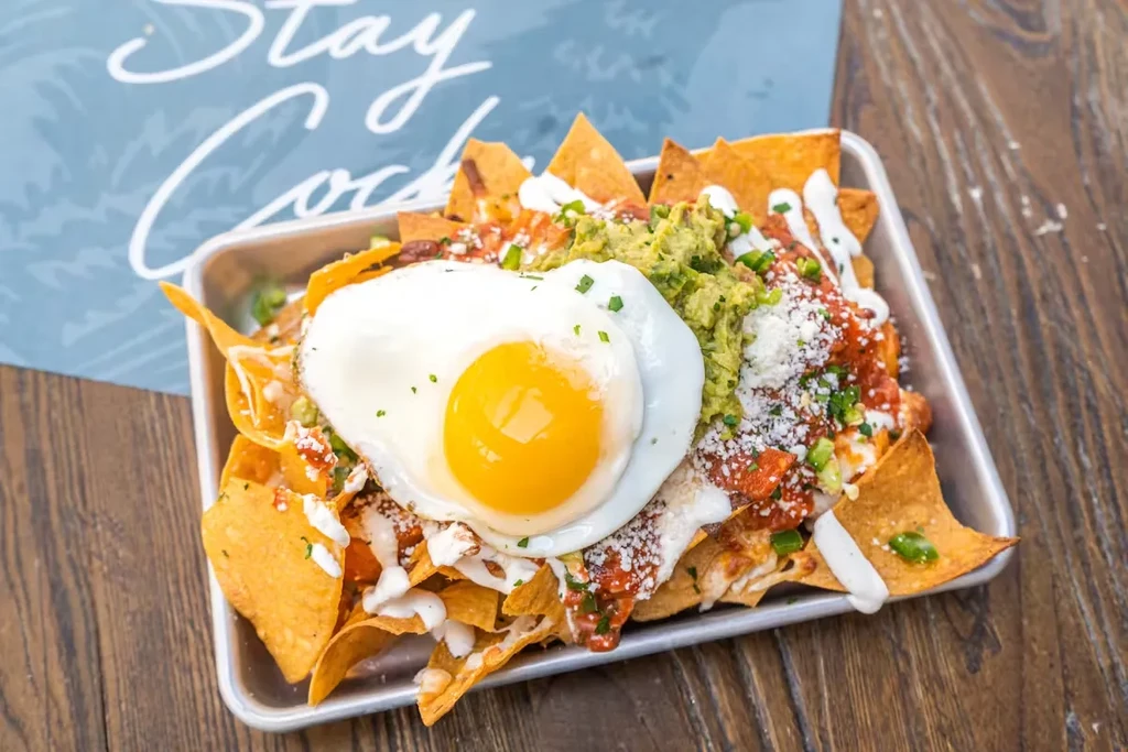 Breakfast nachos in a metal tray with a sunny-side-up egg.