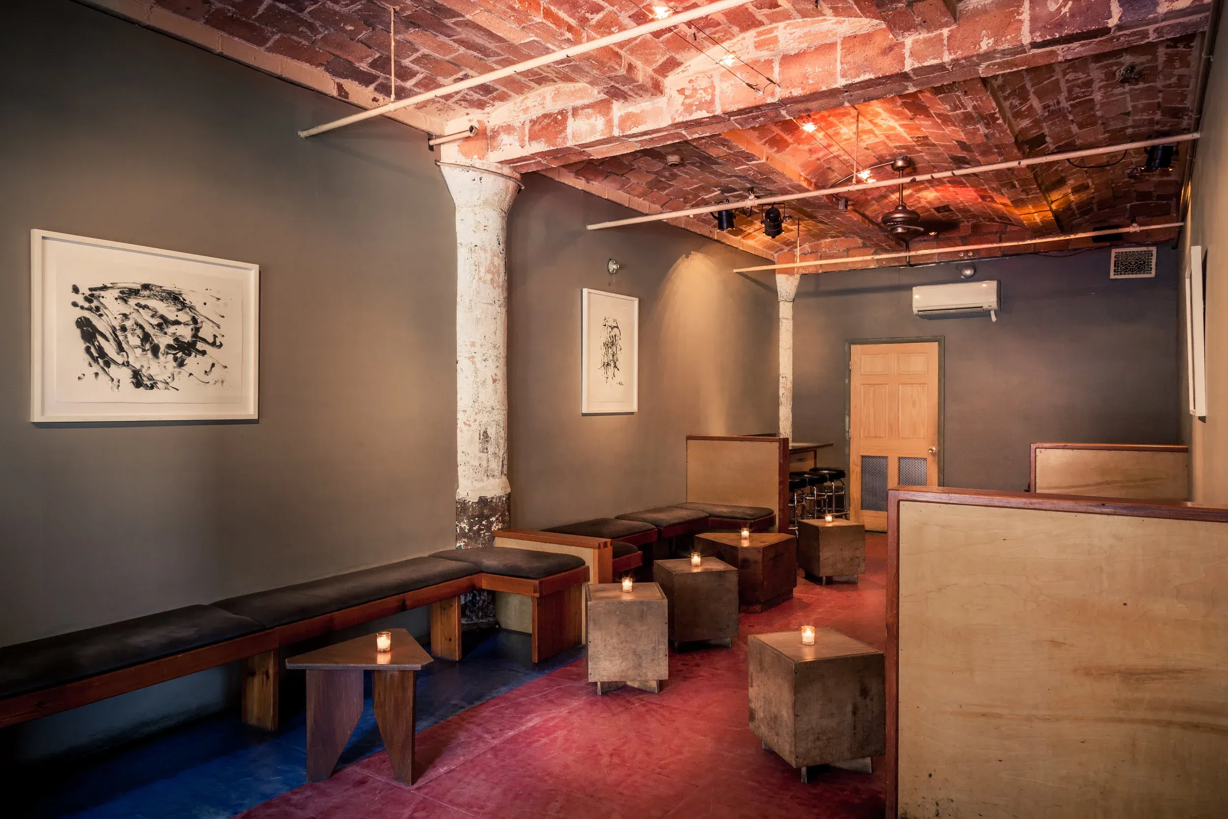 An empty, dimly lit bar with a brick ceiling and red floor.