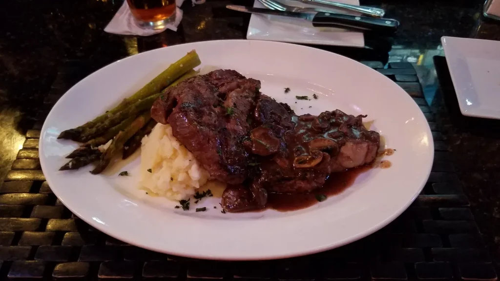 Dark seared meat, dark sauce, mushrooms, mashed potatoes, and asparagus.